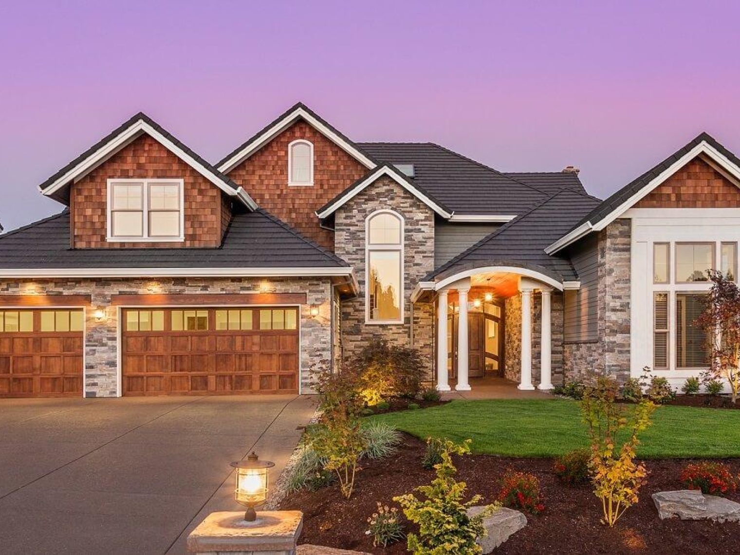 Front view of a luxury home with a purple sunset in the background.