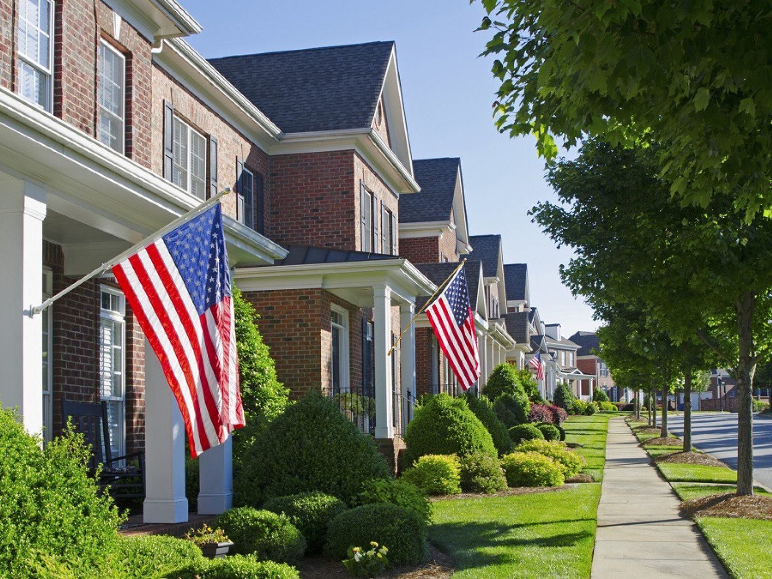 Row of residential homes with American flags.