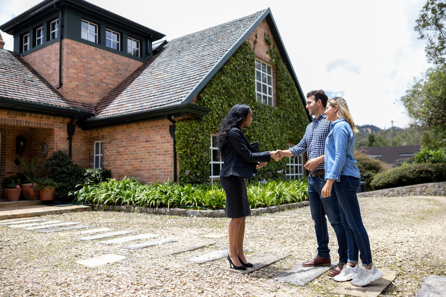 Real estate agent meeting couple outside of a home.