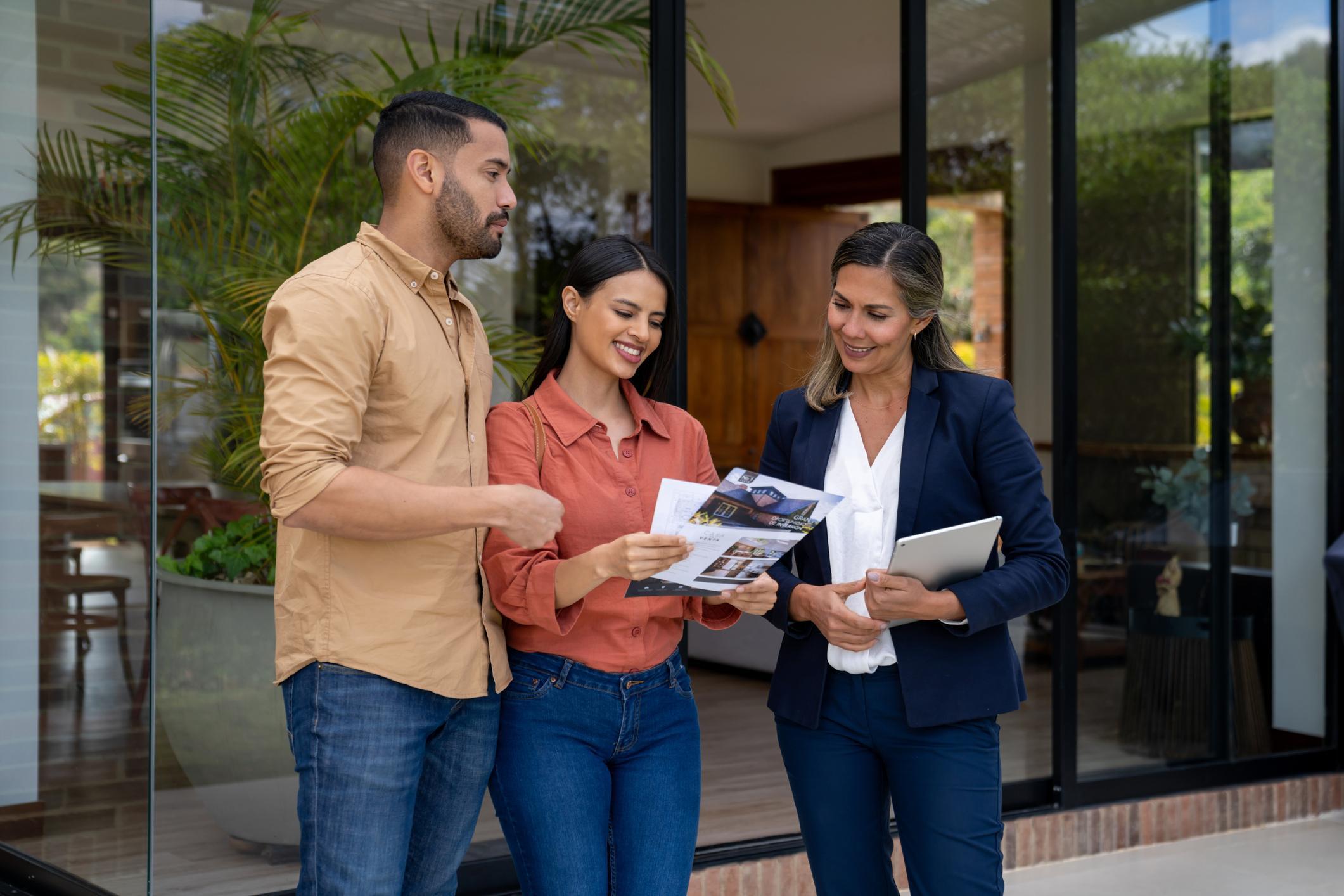Couple talking to a real estate agent while looking to rent a house.